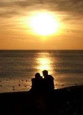 couple-sitting-on-beach-at-sunset-silhouette